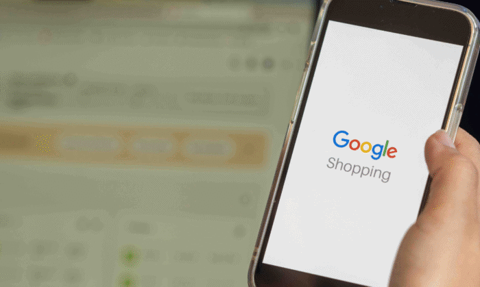Nahaufnahme einer Hand, die ein Handy mit der Google-Shopping-Startseite hält.