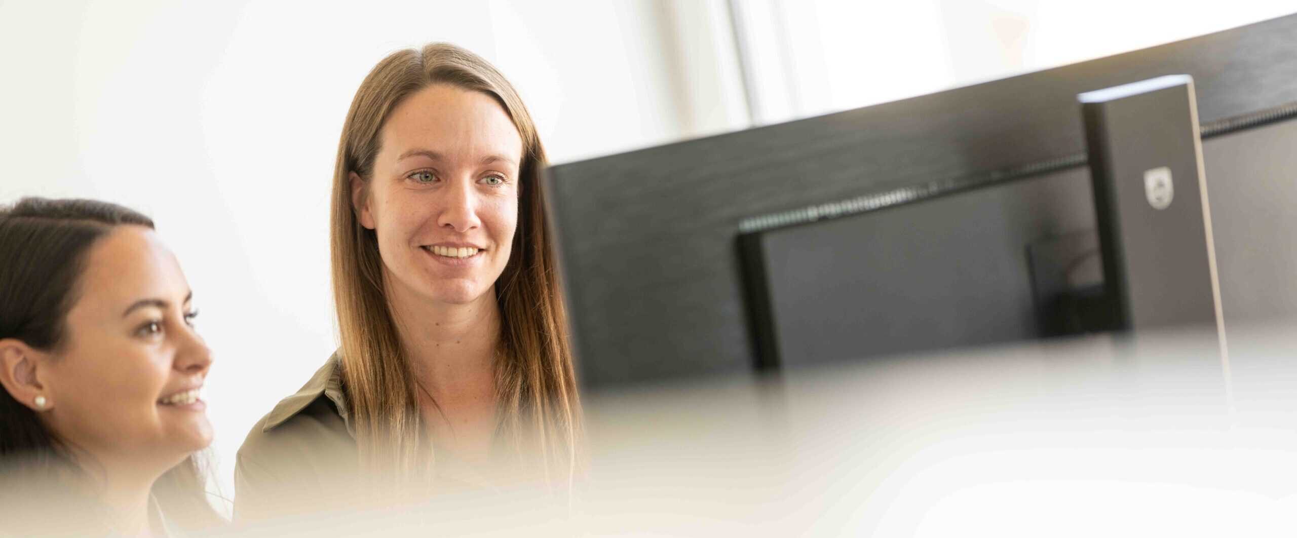 Melanie und Alena schauen zusammen etwas an am Bildschirm.